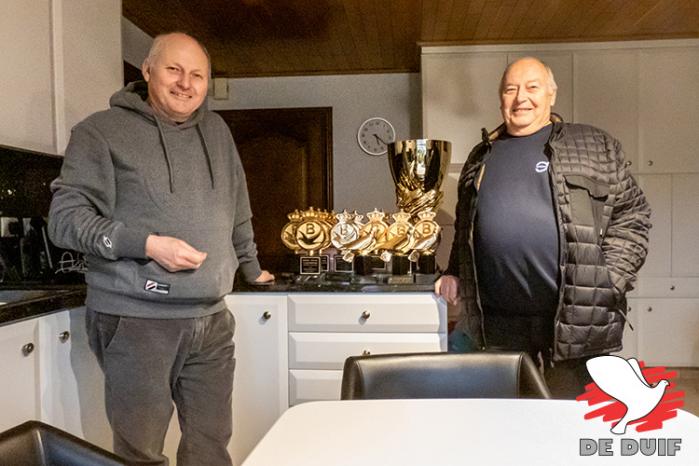 Freddy en Jacques bij hun indrukwekkende verzameling trofeeën. In 2022 werden ze 1e Algemeen kampioen KBDB, 2e Opvolger Gouden Duif en Superstar van het jaar Fond!